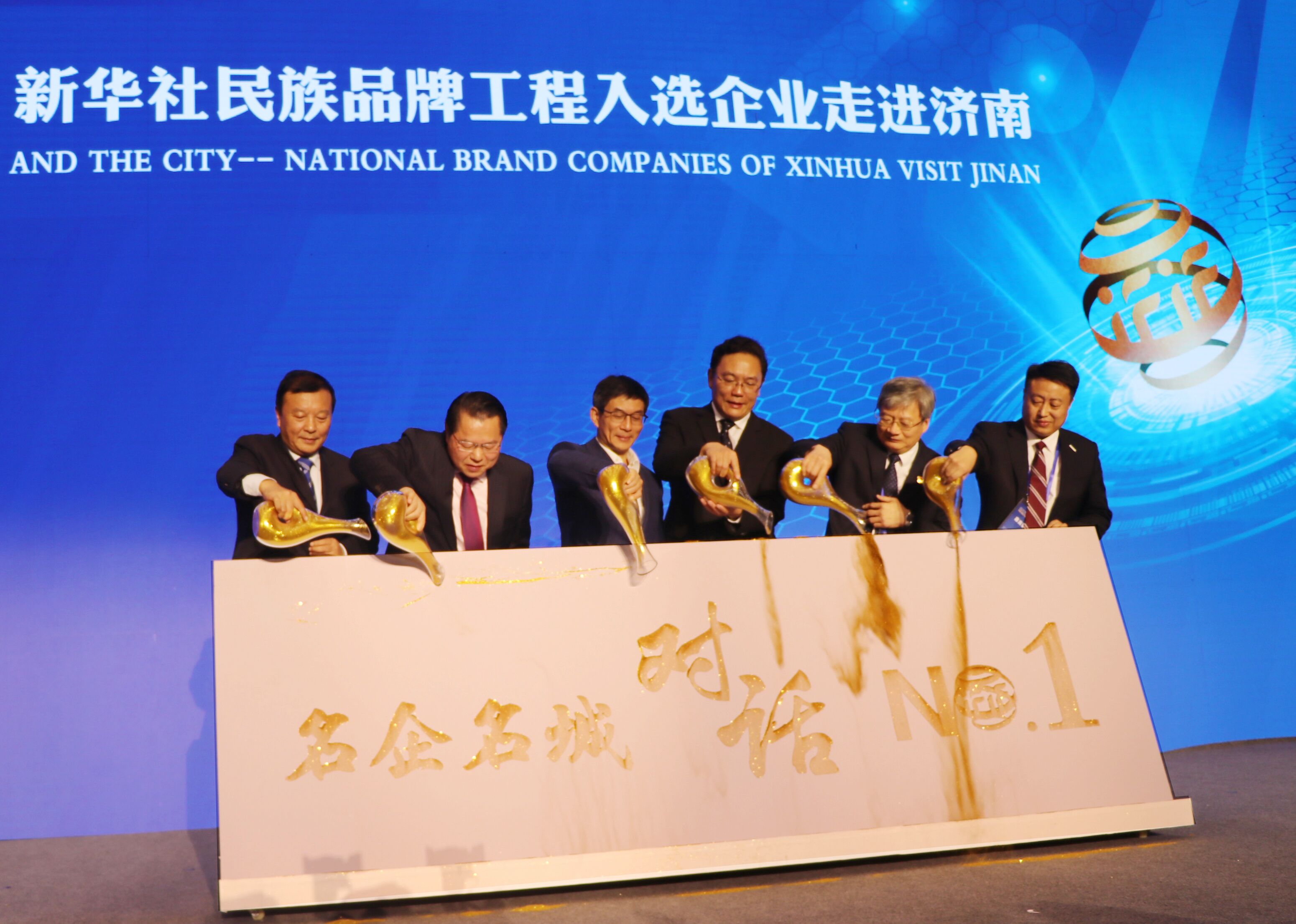 圖為新華通訊社副社長兼秘書長劉正榮（左三），濟南市委常委、副市長，徐群（右三），全國政協(xié)委員、月星集團董事局主席丁佐宏（左二），全國人大代表，江蘇今世緣酒業(yè)董事長、總經(jīng)理周素明（左一），中國重汽集團副總裁宋其東（右二），浪潮集團副總裁盧文杰（右一）共同“澆金”，啟動首期名企名城對話——新華社民族品牌工程入選企業(yè)走進濟南儀式。